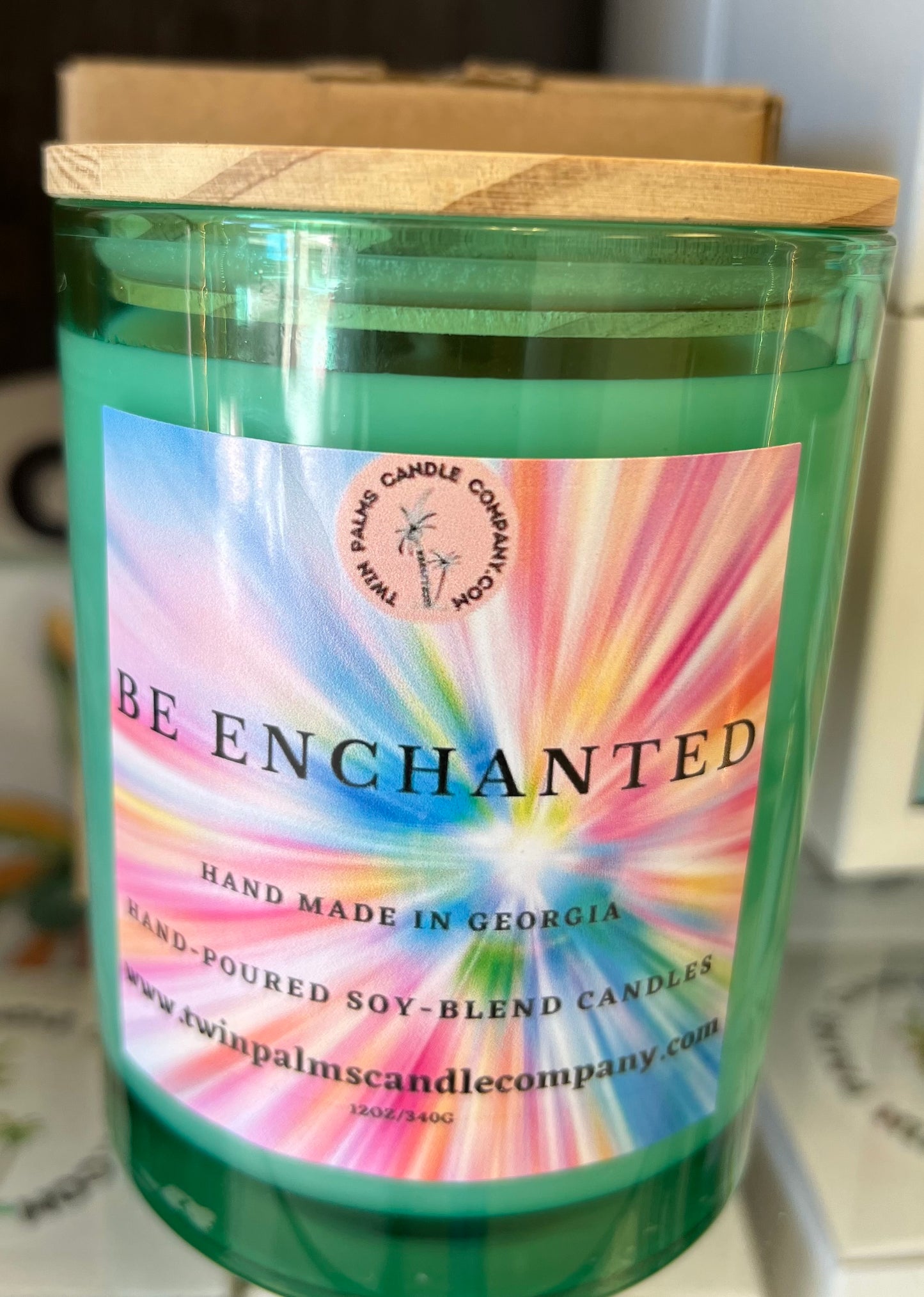 Green candle in a jar from The Bubble Bath Shop's Be Enchanted collection, featuring a decorative label and a lit wick.
